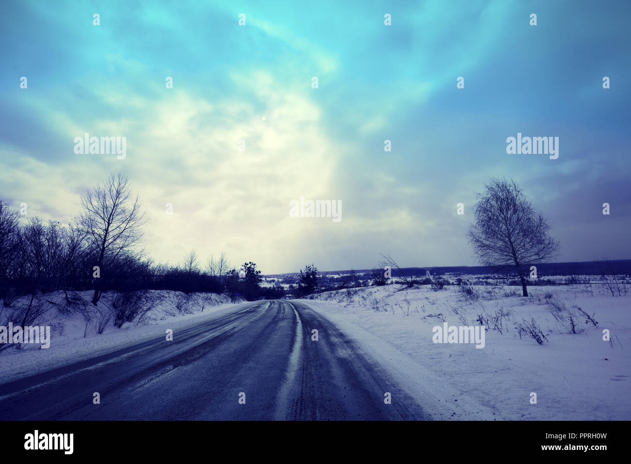 Paesaggio con road e drammatico cielo tempestoso in nevoso inverno Foto Stock