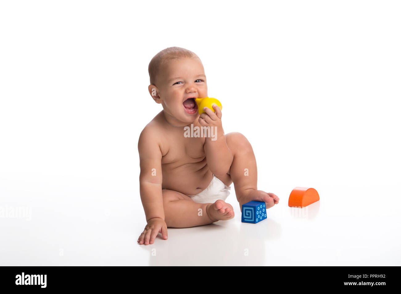 Un ridere sette mesi baby boy giocando con dei blocchi di legno. Girato in studio su un bianco, sfondo senza giunture. Foto Stock