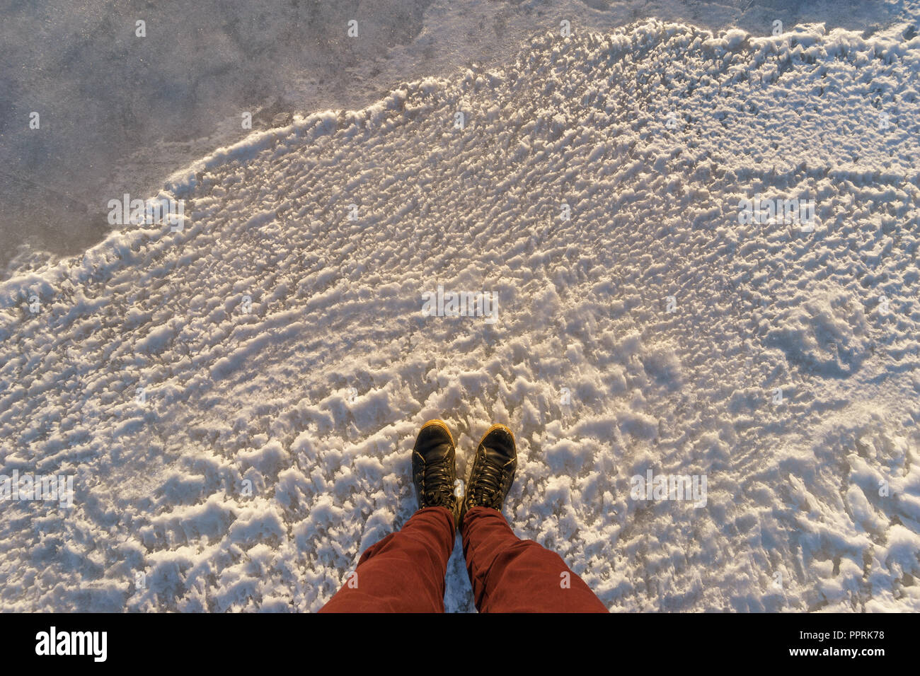 Gambe maschio permanente sulla superficie ghiacciata, pov shot Foto Stock
