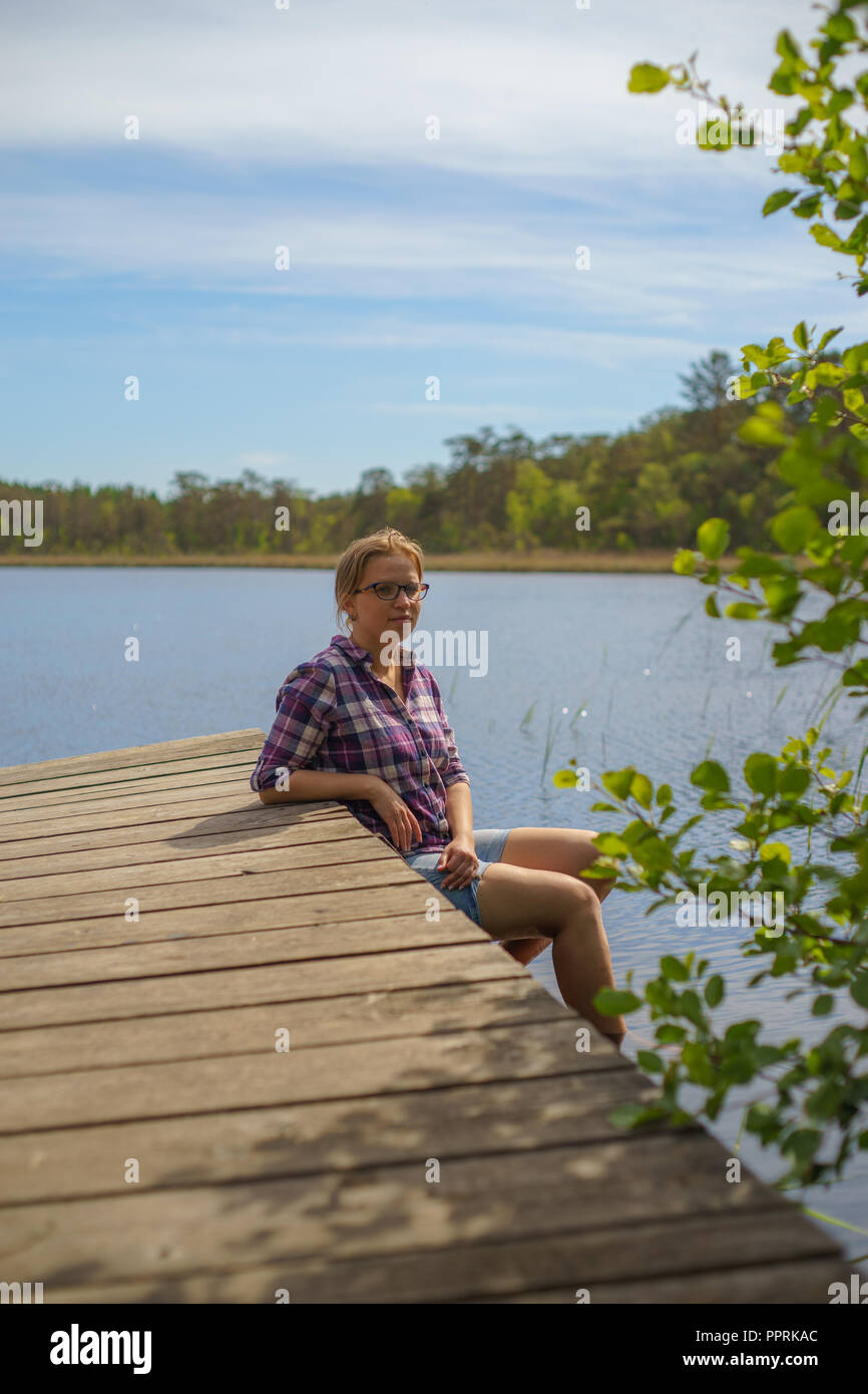 Giovane donna bella rilassante vicino al pittoresco lago, vista verticale Foto Stock