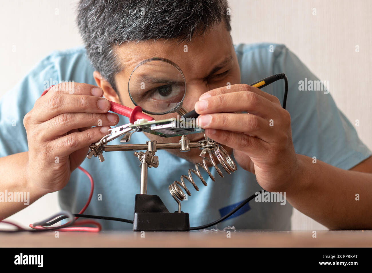Tecnico elettronico lavorando alla riparazione di una scheda Foto Stock
