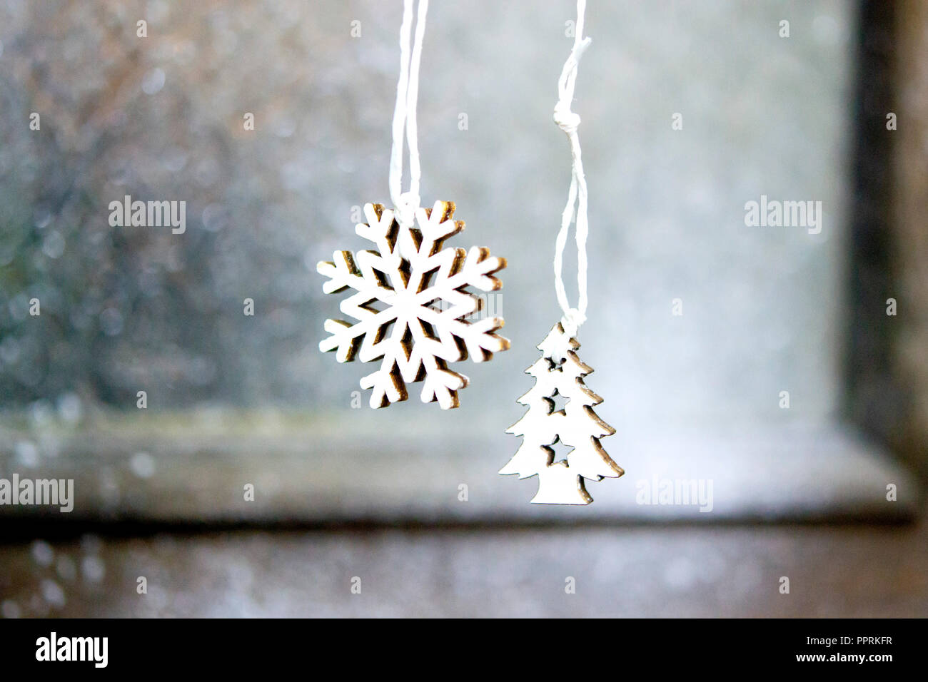 Due piccoli e bianchi alberi di Natale giocattoli appesi sullo sfondo di un muro grigio di sportello di close-up. Sfondo di Natale Inverno Anno Nuovo scenario dello sfondo. Foto Stock