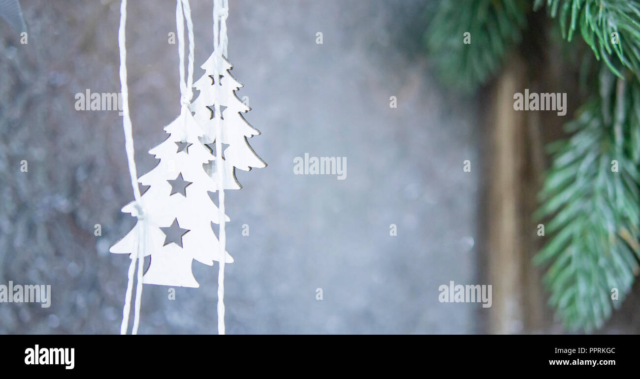 Due piccoli e bianchi alberi di Natale appeso sullo sfondo di un muro grigio con verde di Natale a rami di alberi di close-up. Sfondo di Natale Inverno Anno Nuovo scenario dello sfondo. Foto Stock