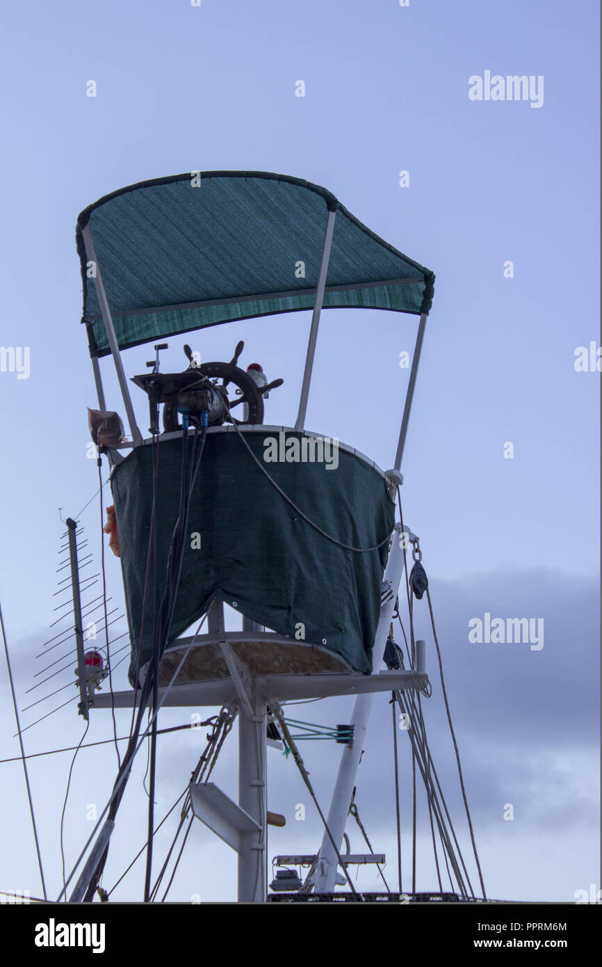 Un ponte del Capitano con un timone hawser affrontare antenna della puleggia scanalata e la tenda di una barca da pesca. Sullo sfondo è il cielo blu con nuvole. Foto Stock