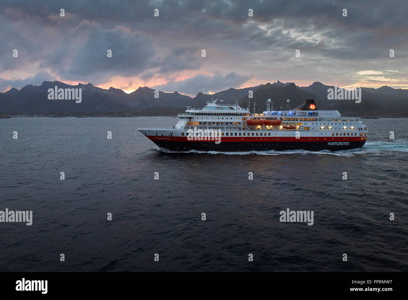 Il traghetto Hurtigruten, la signora FINNMARKEN, parte sud da Svolvær. Le suggestive montagne delle isole Lofoten e il sole di mezzanotte dietro la Norvegia. Foto Stock