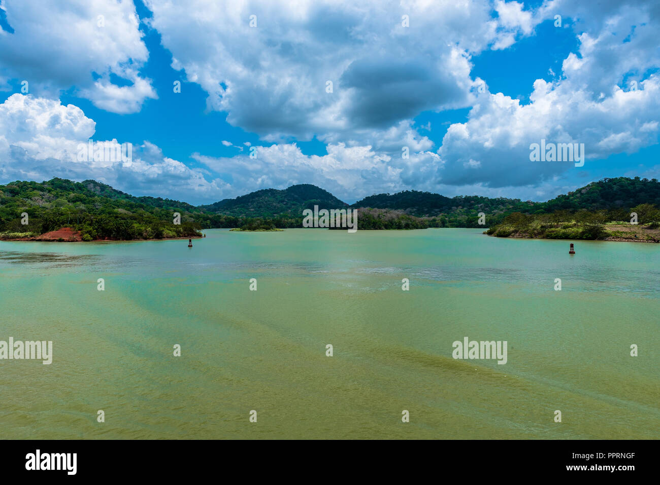 Il verde blu delle acque del Lago di Gatun sono sul display sotto un dramtic cielo blu con il bianco puffy nuvole. Foto Stock