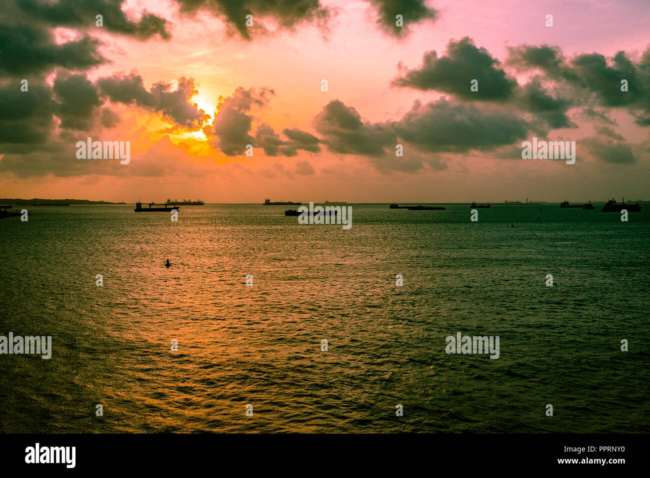 Il sole illumina il cielo con colori pastello pallido come si imposta verso il basso sopra il porto di Colon. Foto Stock