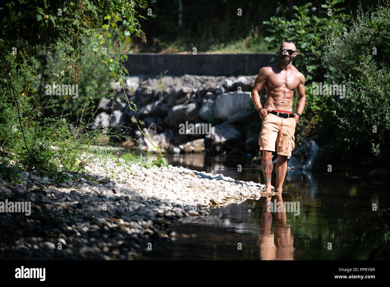 Sano giovane uomo in piedi forti muscoli di flessione - Atletico muscolare Bodybuilder Modello di Fitness in posa all'aperto Foto Stock