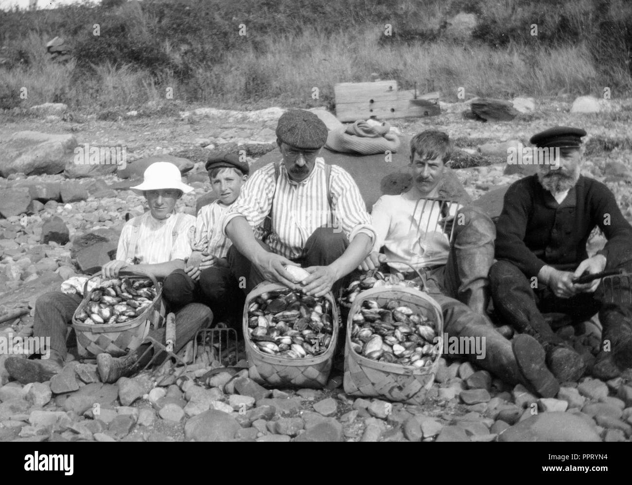 Un gruppo di uomini e ragazzi posano con bottino di vongole sulla costa orientale degli USA, ca. 1905. Foto Stock