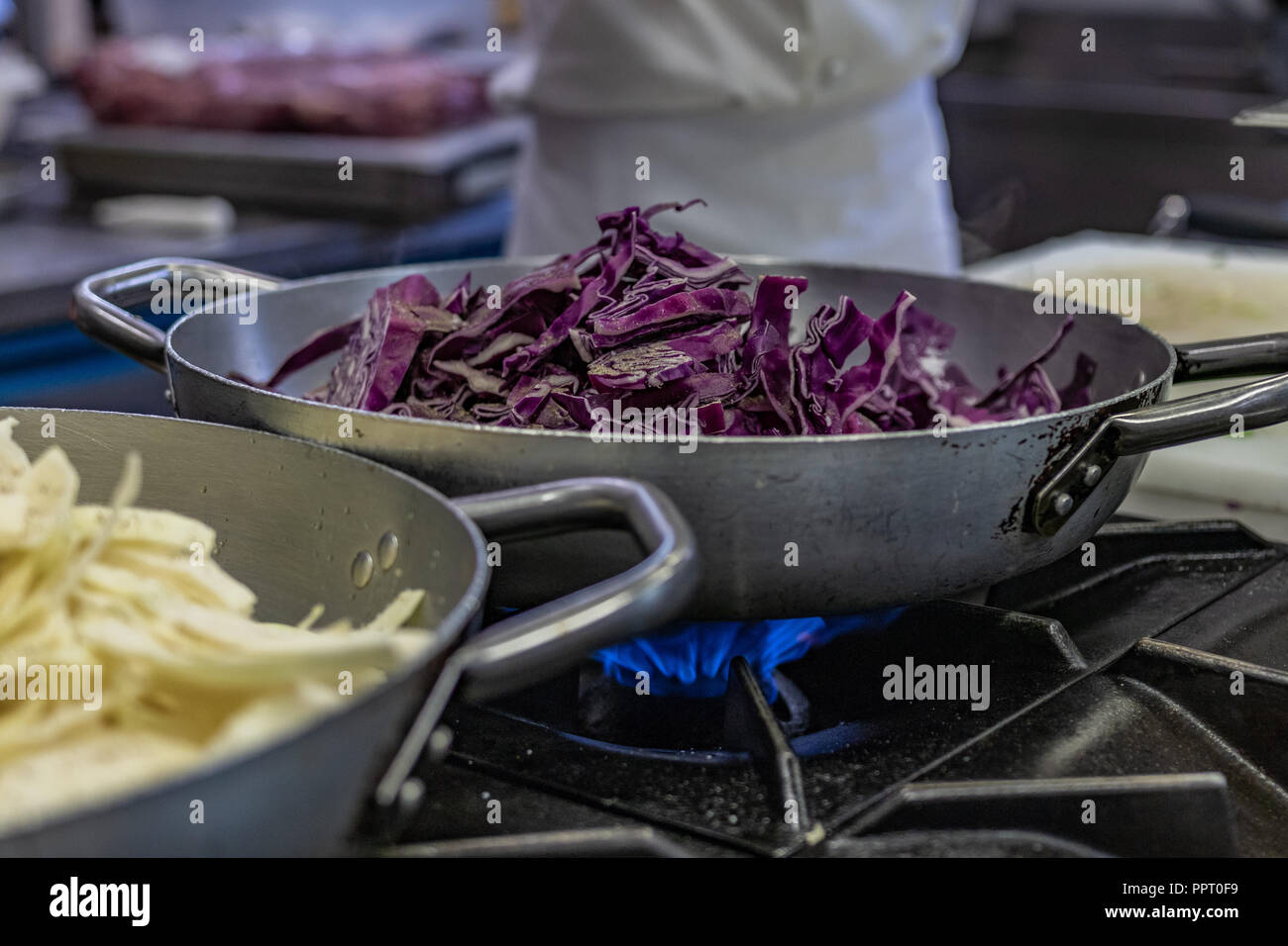 I rifugiati politici sfuggiti dall Africa a bordo di una barca. Trovato accoglienza e lavoro in Europa. Ristorante vegano, cuoco partecipante, acciaio pentolame e stoviglie, il bruciatore a gas. Foto Stock