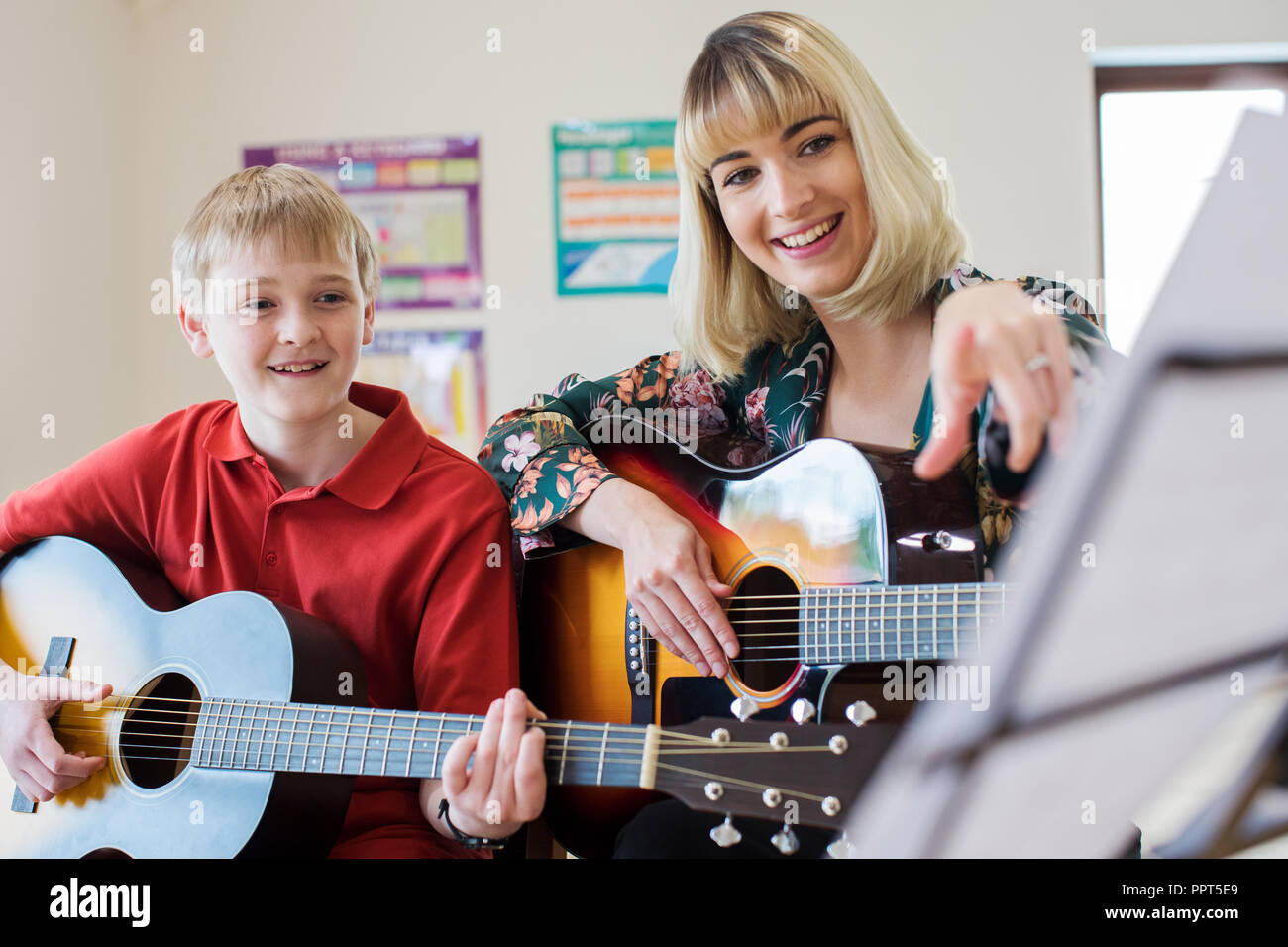 Docente aiutare studenti maschi a suonare la chitarra in lezione di musica Foto Stock