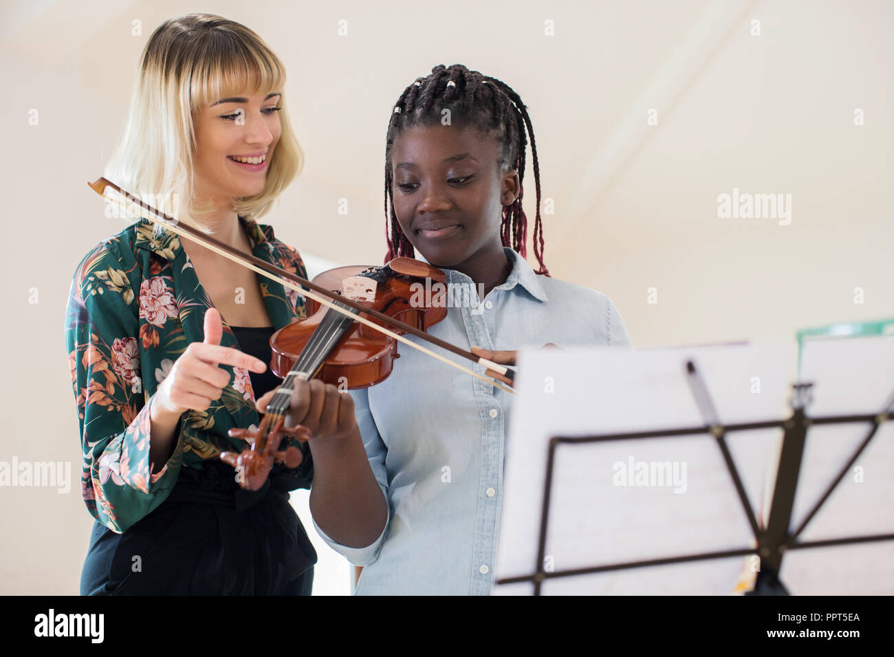 Il tutor insegnamento studente di scuola superiore per la riproduzione di violino nella lezione di musica Foto Stock