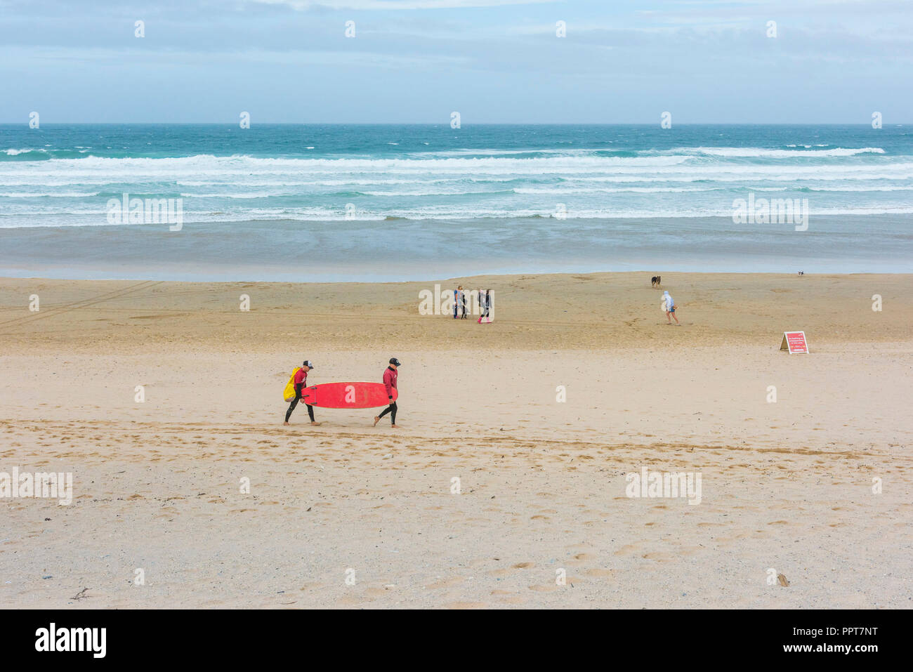 Due istruttori che trasportano le tavole da surf torna a Fistral Beach Surf School in Newquay in Cornovaglia. Foto Stock