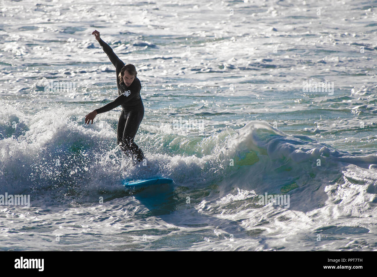 Un surfista a cavallo di un onda al Fistral a Newquay in Cornovaglia. Foto Stock