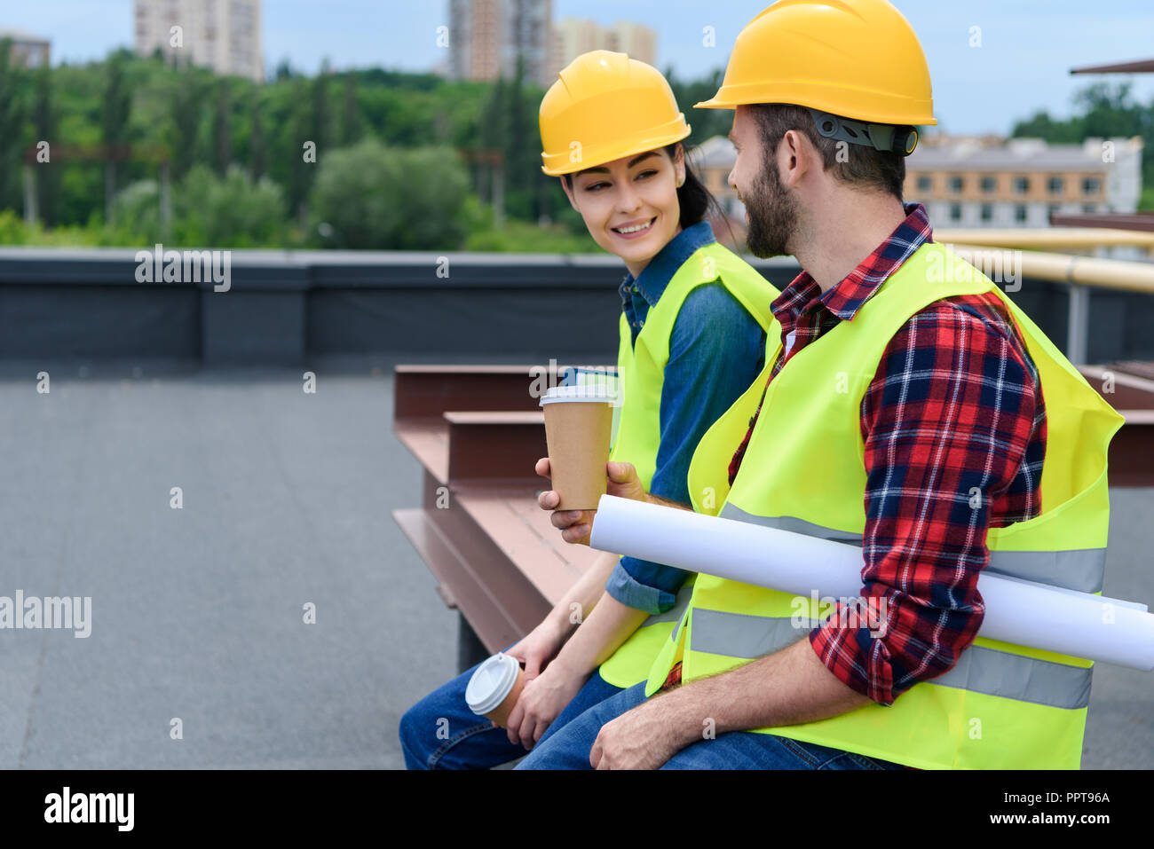 Gli architetti in caschi con blueprint su pausa caffè seduti sul tetto Foto Stock