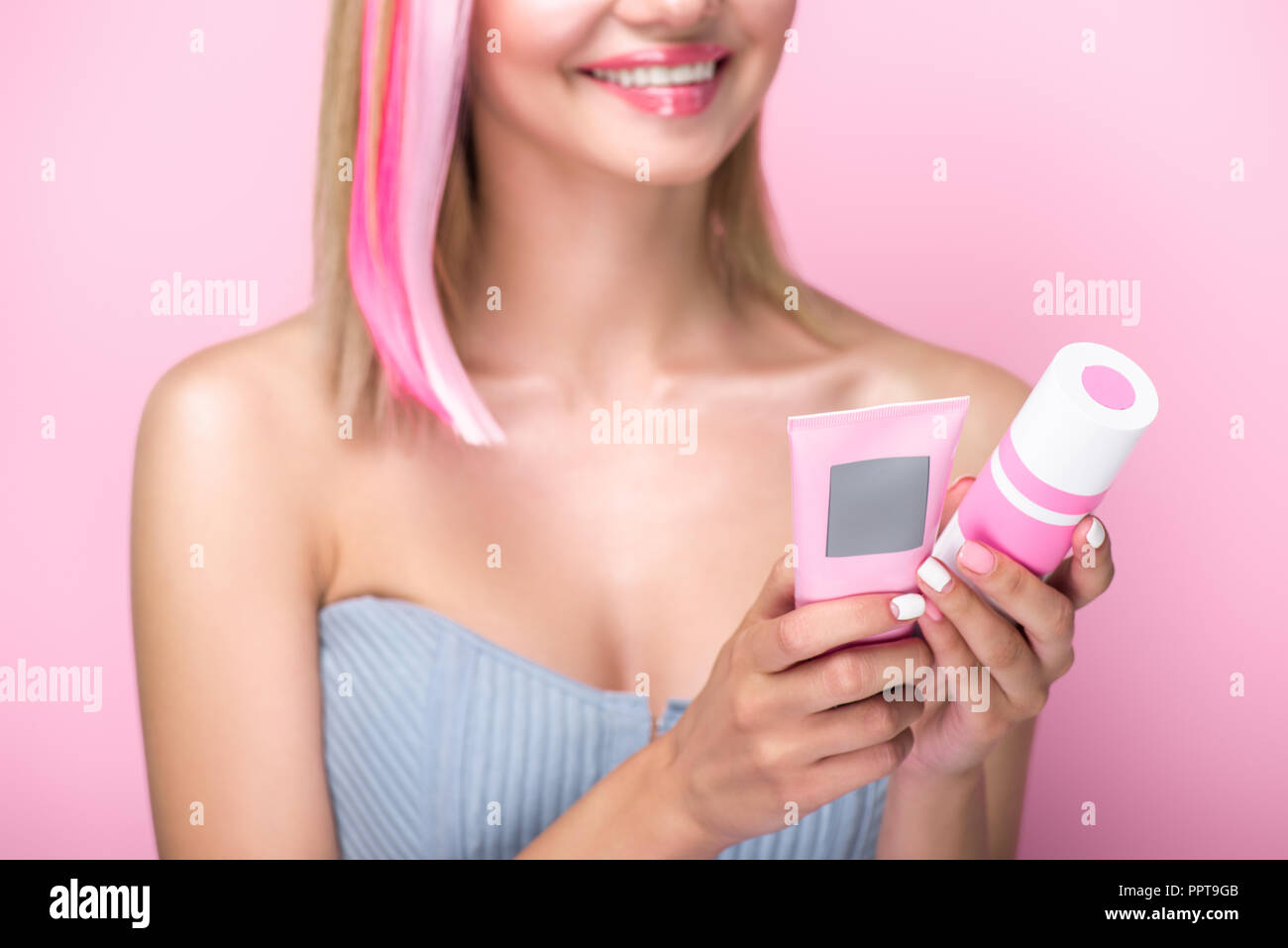 Ritagliato colpo di giovane donna con colorate ciocche di capelli azienda trattamenti dei capelli isolato in rosa Foto Stock