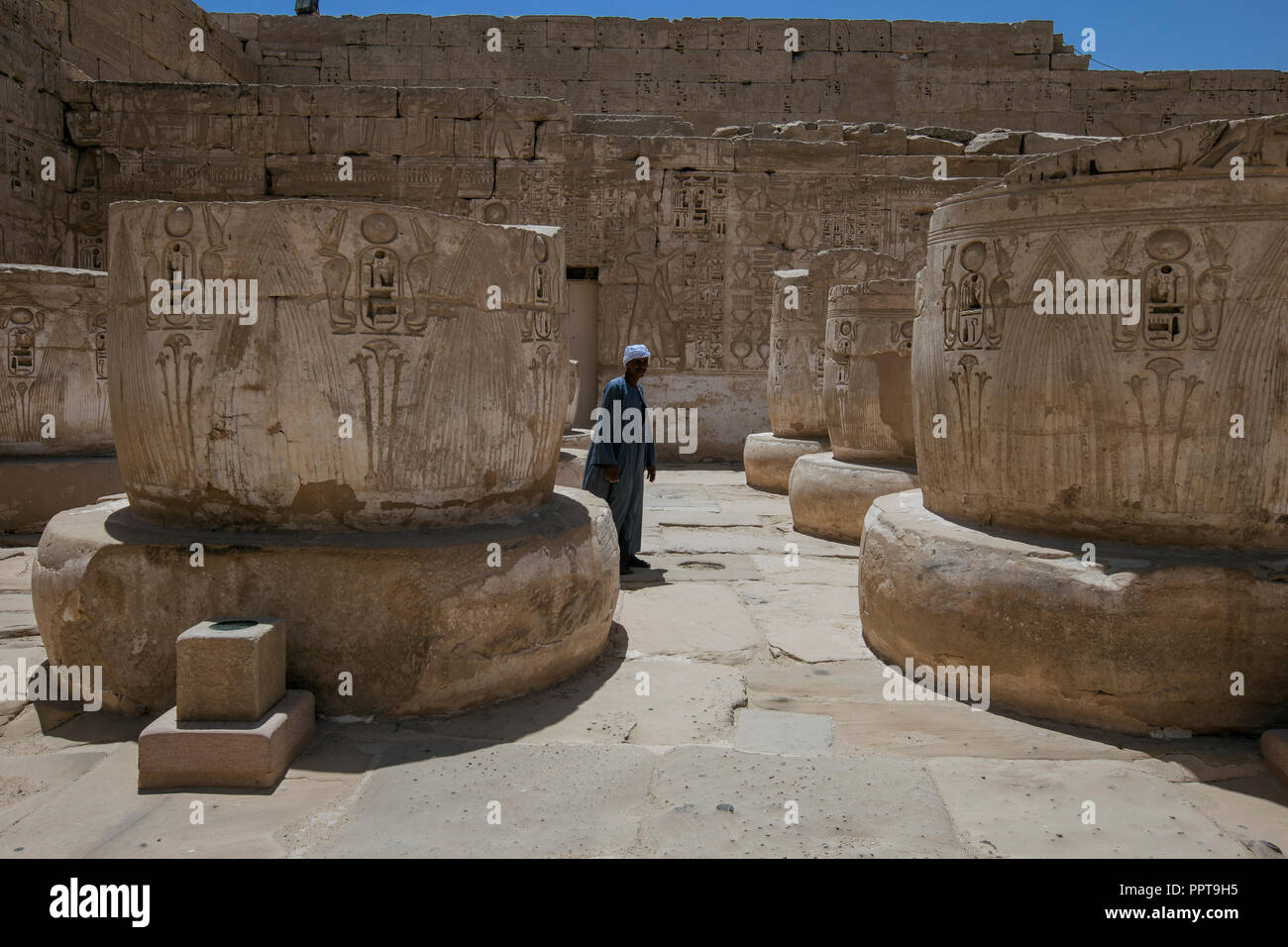 Uomo egiziano a piedi attraverso il cortile di cut-off colonne in Medinet Habu tempio di Ramses III a Luxor, Egitto. Foto Stock