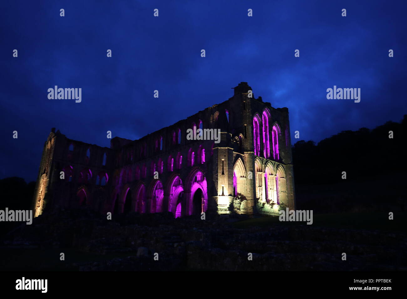 Rievaulx Abbey inondate di luce colorata in anticipo di Rievaulx illuminante, a tre notte luce e suono installazione presso l abbazia del XI secolo rovine nel North Yorkshire. Foto Stock