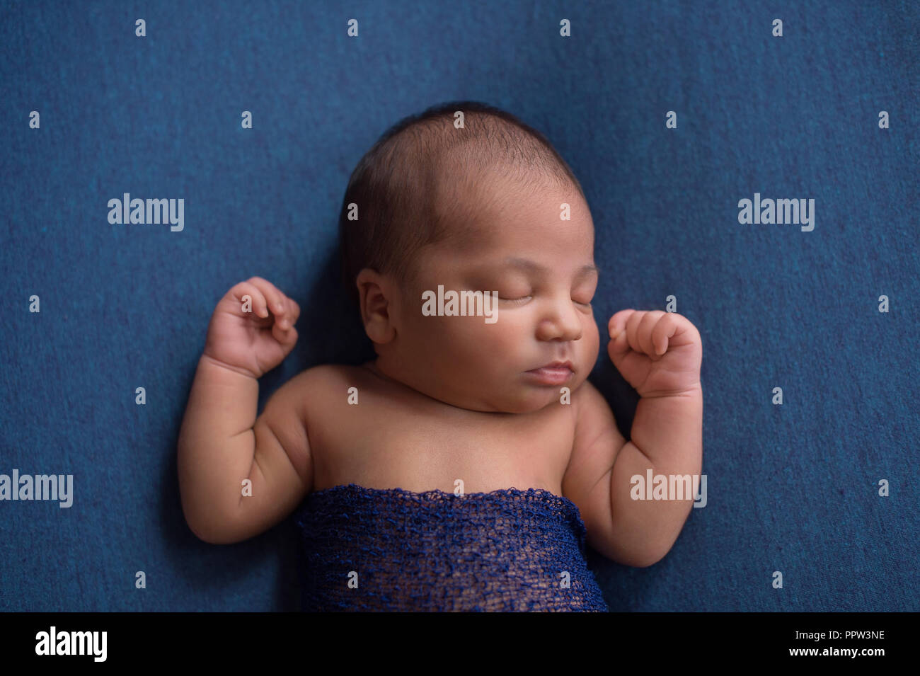 Colpo di testa di un sonno, nove giorni di età neonato ragazzo. Girato in studio su denim materiale blu. Foto Stock