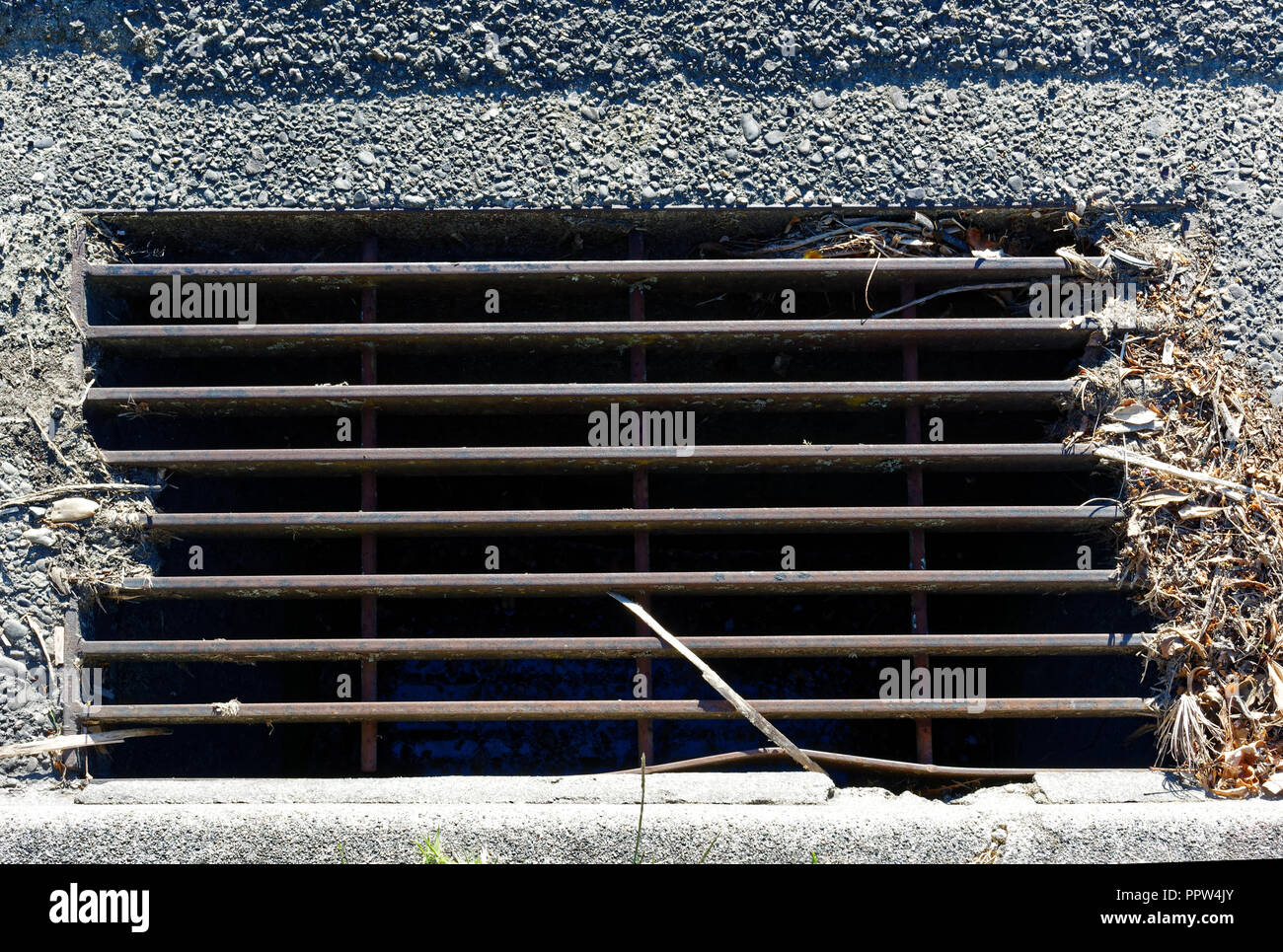 Il drenaggio della strada, una griglia di scarico acque piovane con un bastone in esso. Foto Stock