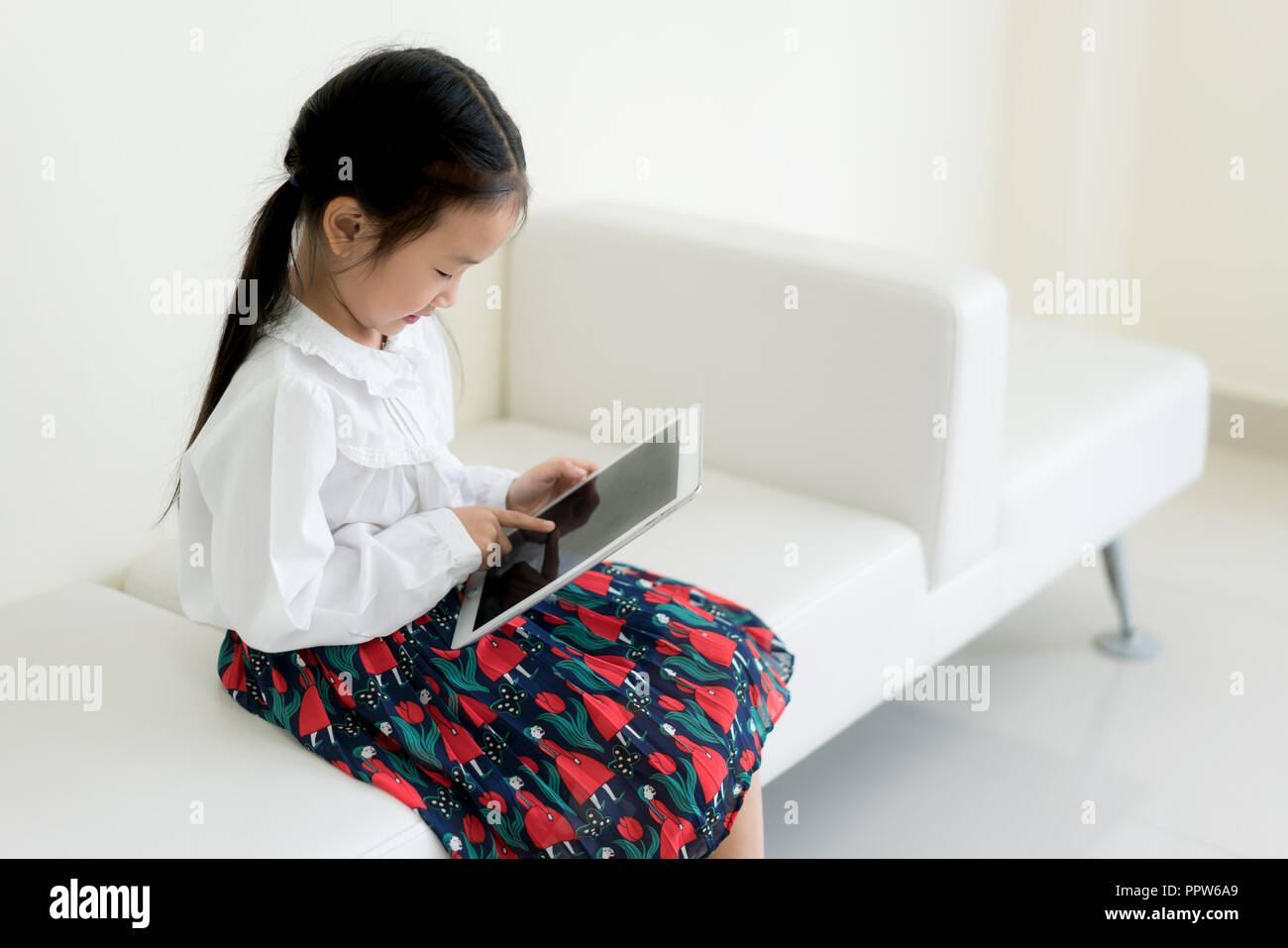 Asian bambina la riproduzione digitale compressa a casa. Istruzione, scienza, tecnologia, i bambini e le persone del concetto. Foto Stock