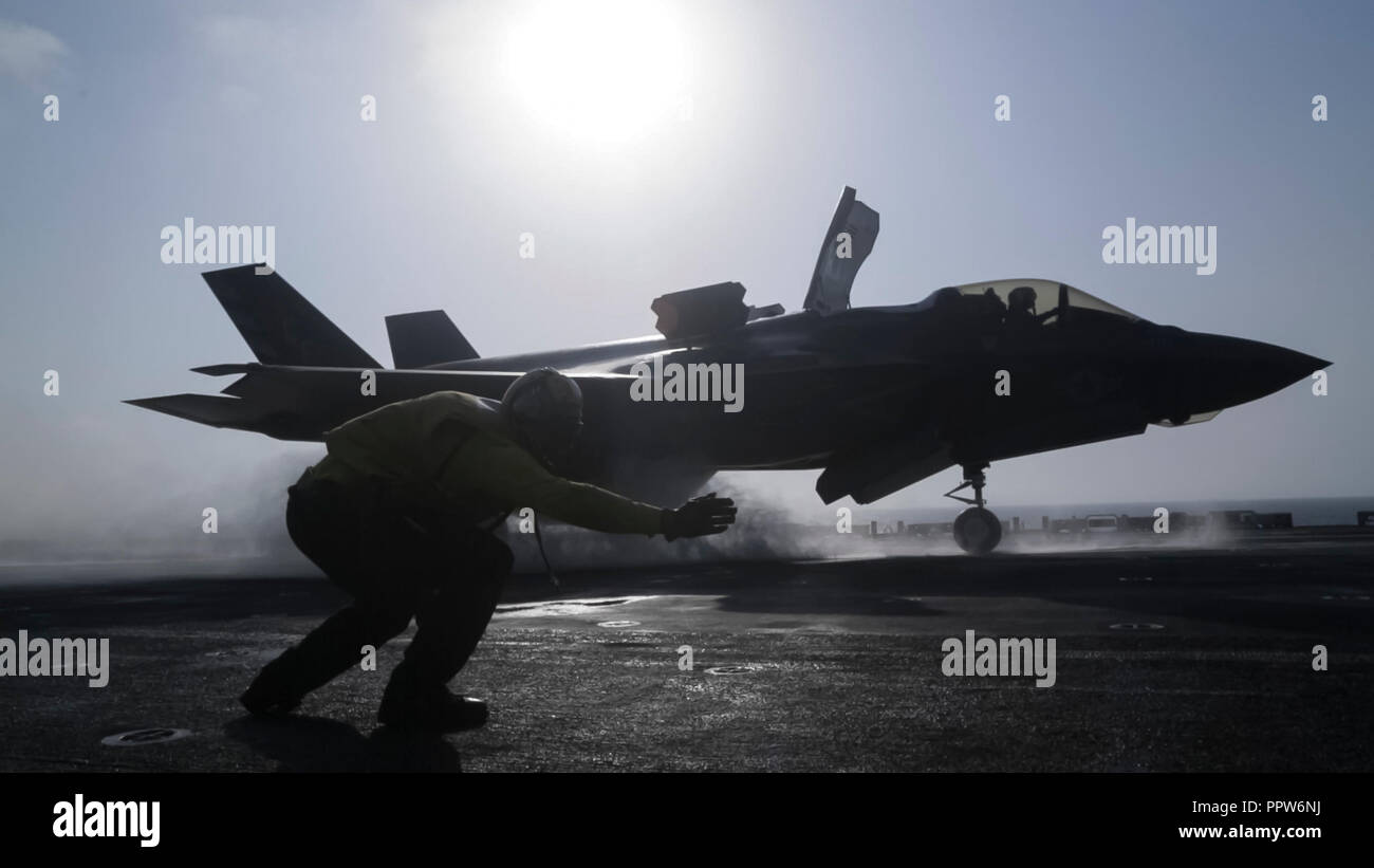 Stati Uniti Quinta Flotta AREA DI OPERAZIONI - STATI UNITI Navy Petty Officer 1. Classe Rey bianco, un aviation nostromi mate gestore con la Essex anfibio gruppo pronto (ARG), lancia un F-35B Lightning II con Marine Fighter Squadron di attacco 211, 13 Marine Expeditionary Unit (MEU), da The Wasp-classe assalto anfibio nave USS Essex (LHD 2), dinanzi alla F-35B del primo sciopero di combattimento, Sett. 27, 2018. L'Essex è il fiore all' occhiello per la Essex anfibio gruppo pronto e, con l'avviato XIII MEU, è distribuito negli Stati Uniti Quinta Flotta area di operazioni a sostegno di operazioni navali per assicurare la stabilit marittima Foto Stock