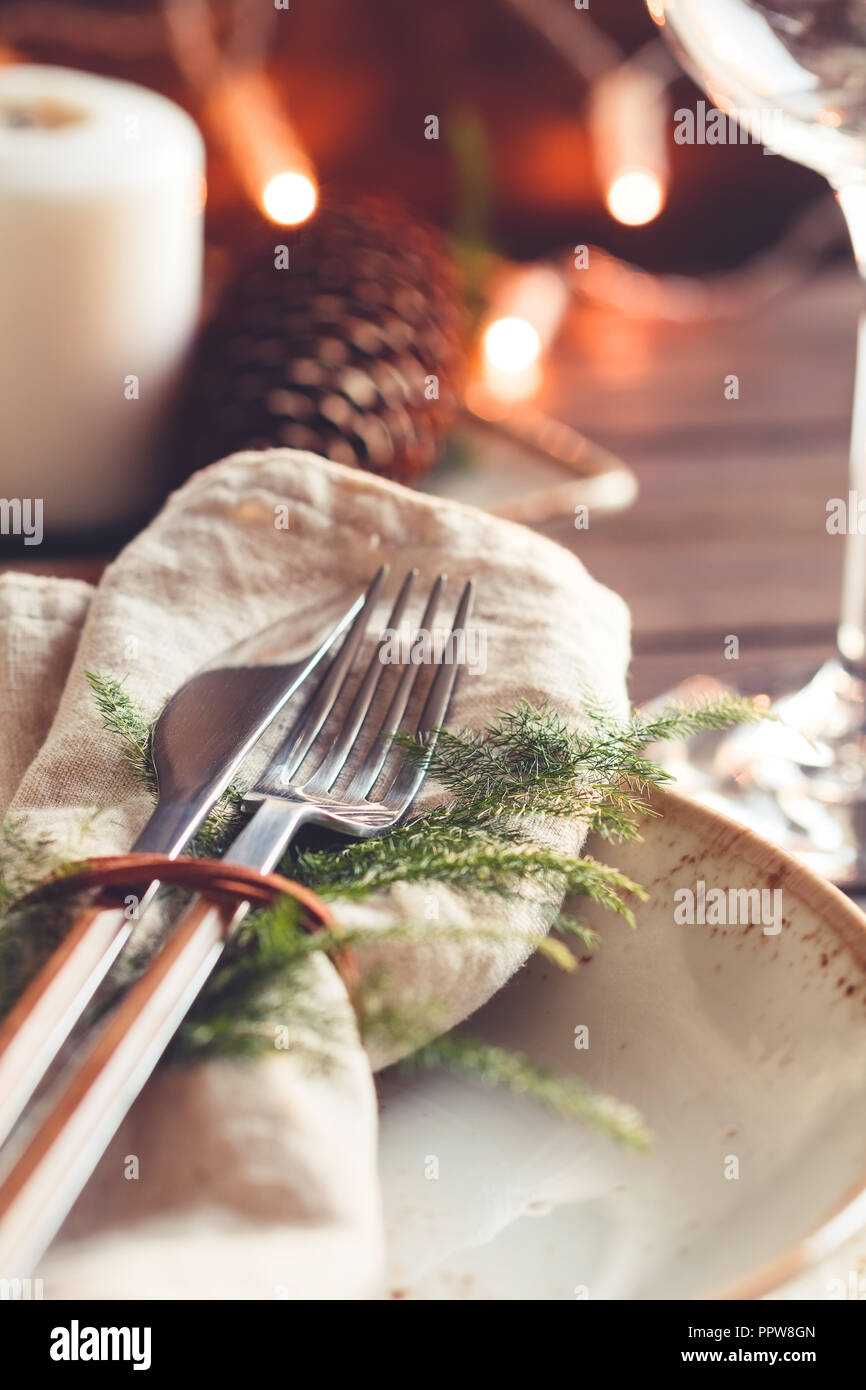 Ringraziamento impostazione tabella tra candele bianche e i coni. Piastra in ceramica con coltello e forchetta su un tovagliolo di lino. Close up. Foto Stock