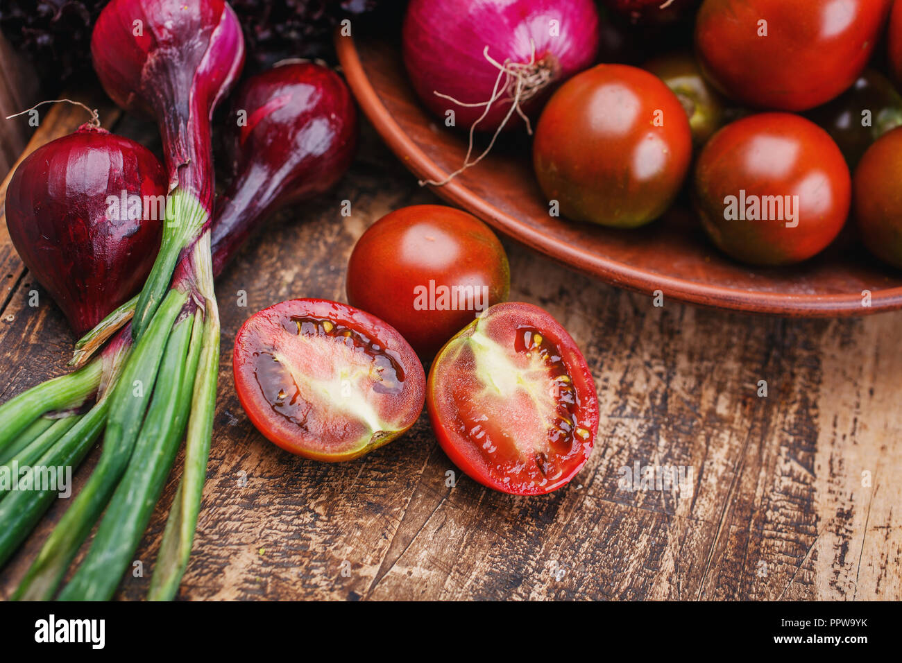 Su una tavola di legno si trova di verdure fresche. Pomodoro tagliato in due parti. Foto Stock