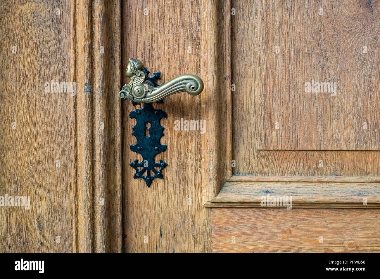 Guardando un ferro nero maniglia di porta di una porta di legno di un edificio nella città di Thun in Alpi Bernesi, Svizzera. Si tratta di una bella porta vintage Foto Stock