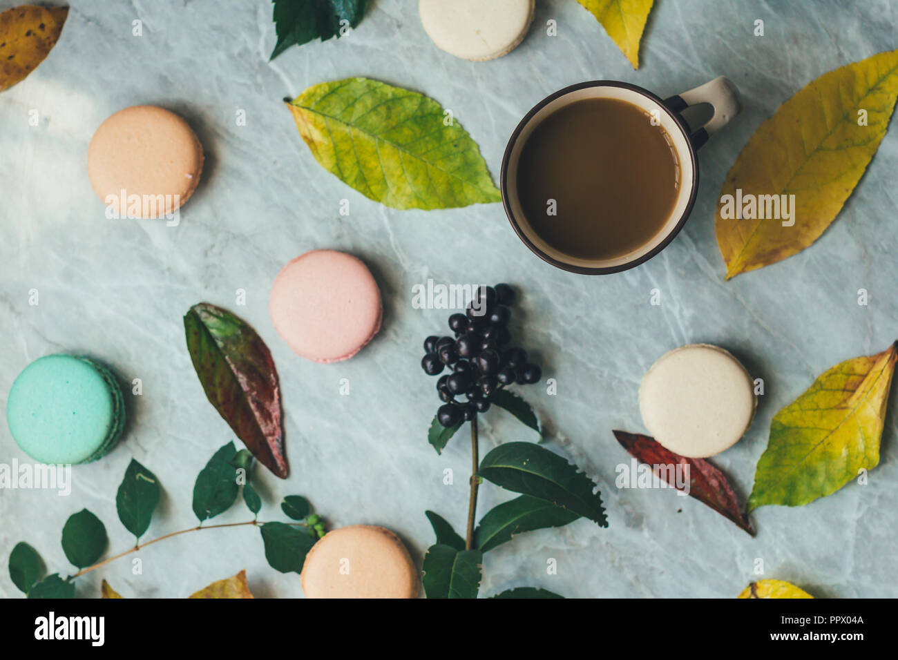 Giallo autunno foglie, una tazza di caffè e pastello macarons francese torte su un piano di marmo. Piano di composizione dei laici dal di sopra, vista dall'alto . Foto Stock