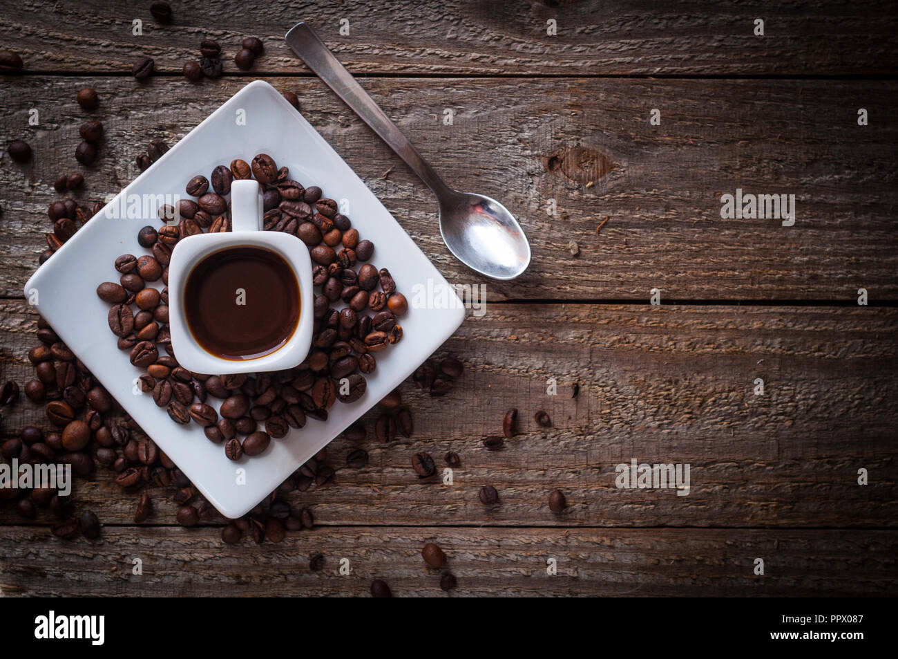 Vista dall'alto di un quadrato tazza di caffè torrefatto in grani e cucchiaio Foto Stock