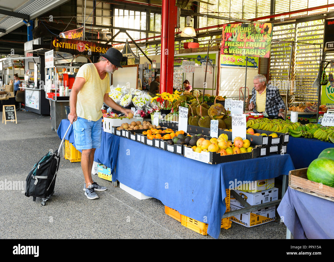 Cliente maschio esaminando la frutta a popolare di Rusty sul mercato Sheridan Street, Cairns, estremo Nord Queensland, FNQ, QLD, Australia Foto Stock