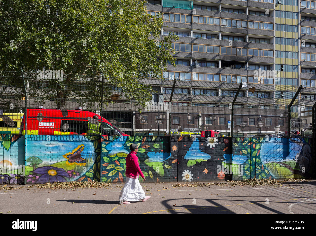 Un locale residente estate passeggiate passato i danni del fumo conseguenze sull'esterno di una superficie piana di incendio in uno dei due blocchi Wendover in Alsazia strada a Aylesbury station wagon, Southwark SE17, il 24 settembre 2018, a Londra, in Inghilterra. Parte di un livello diviso sul piatto il quarto e il quinto piano del 15 piani di blocco è stato danneggiato. Una donna e due bambini rimasti di proprietà prima di brigata arrivati. Essi sono stati trattati presso la scena per inalazione di fumo da Londra un servizio di ambulanza equipaggi e prese troppo ospedale. Un altro uomo è stato anche trattato presso la scena per inalazione di fumo. Foto Stock