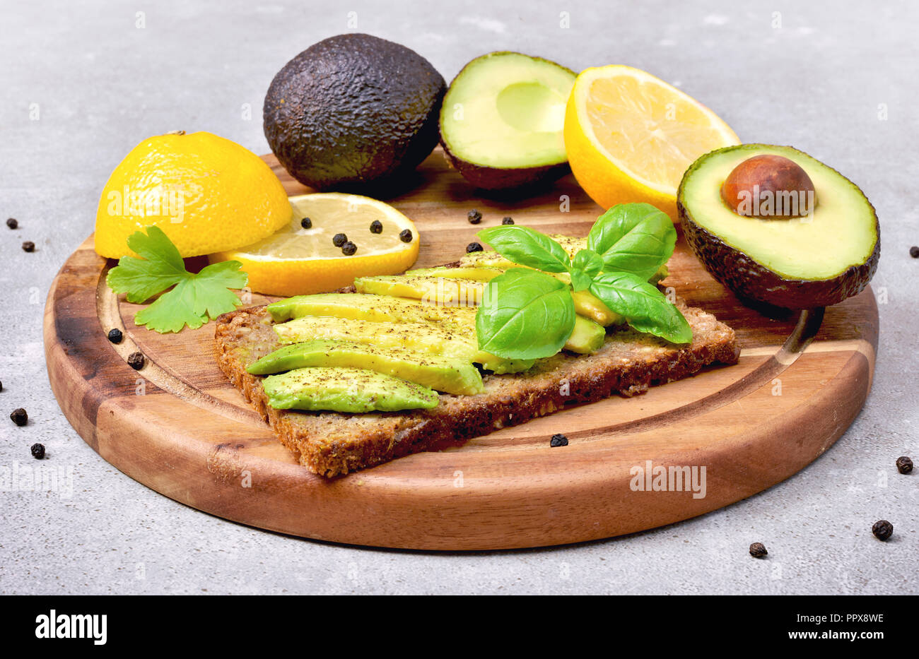 Freschi e deliziosi pasti di avocado, pane e frutto di avocado su un tagliere di legno. Sezione trasversale di avocado e limone, mangiare sano o lifestyle tema Foto Stock