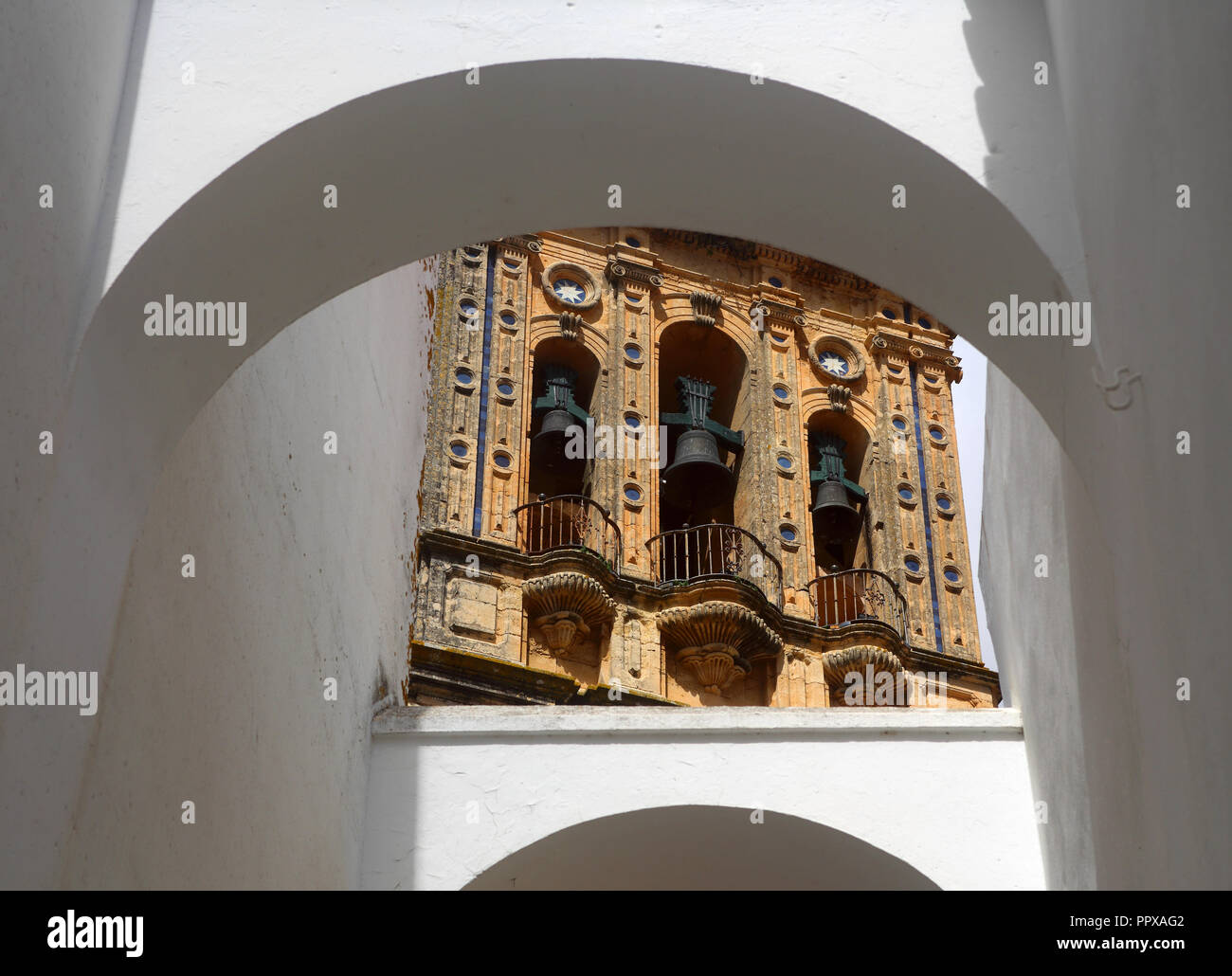 Archi imbiancati e incorniciatura di parete il campanile di Santa Maria Mayor chiesa nel centro storico di Arcos de la Frontera, Andalusia, Spagna. Foto Stock