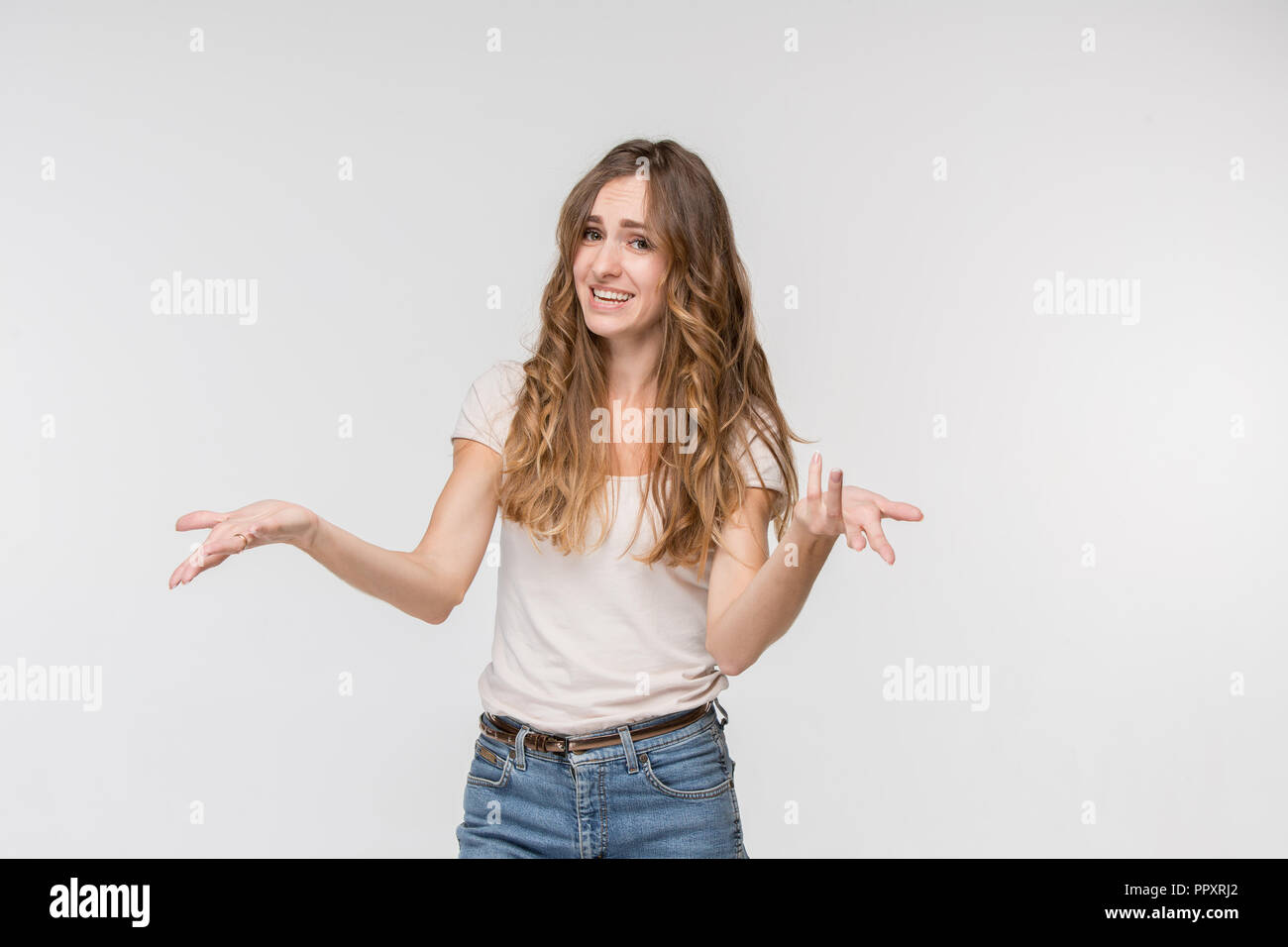 Il motivo è che. Bellissima femmina di metà lunghezza ritratto isolato su bianco studio backgroud. Giovani sorpreso emotivo, frustrato e disorientati donna. Le emozioni umane, espressione facciale concetto. Foto Stock