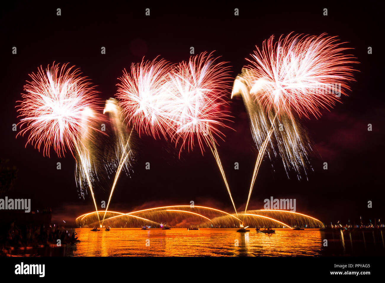 Palle di fuoco e la pioggia di fuoco di fuochi d'artificio a un lago Foto Stock