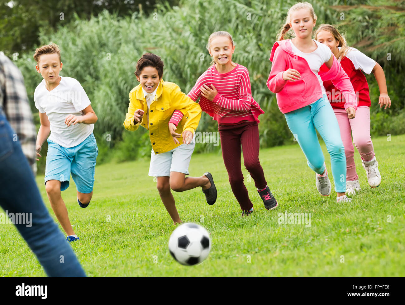 Società di allegro dei bambini che giocano a calcio sul parco giochi nel parco Foto Stock