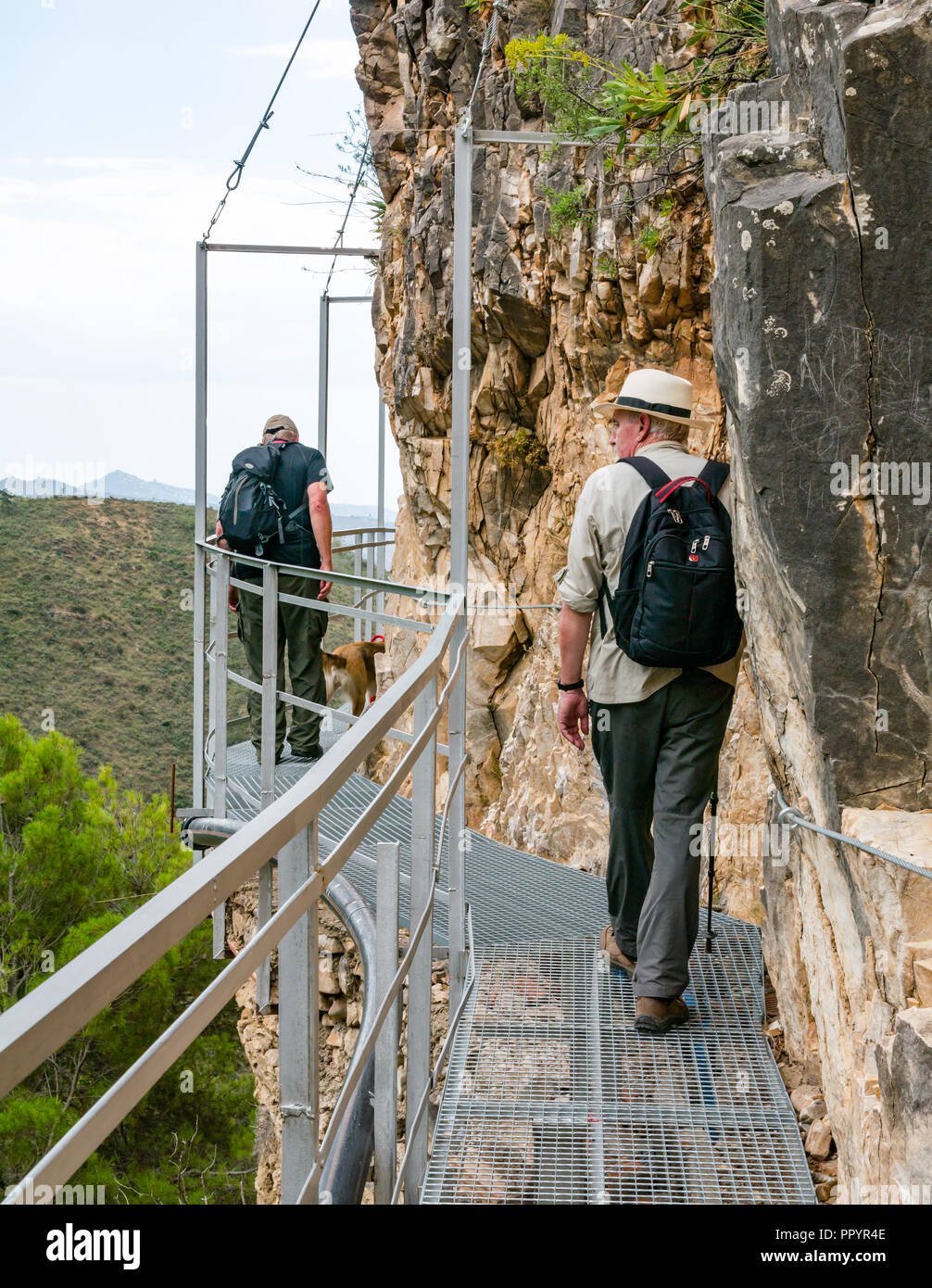 Gli uomini più anziani camminando sulla gola di montagna scogliera passerella metallica, Sierras de Tejeda parco naturale, Axarquia, Andalusia, Spagna Foto Stock
