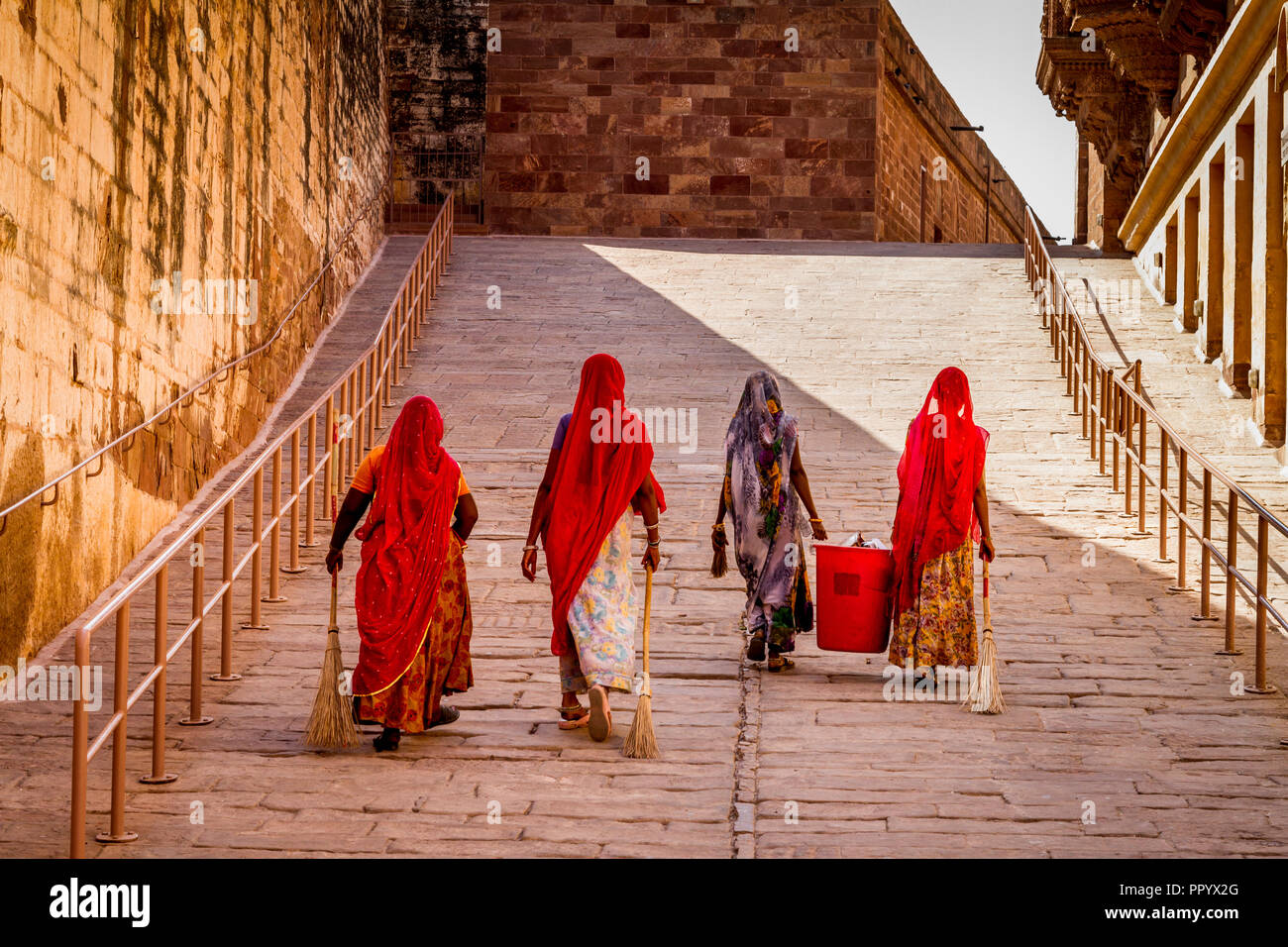 Pulizia indiano ladies salire a piedi a rampa in abiti colorati Meherangarh Fort, Jodhpur Foto Stock