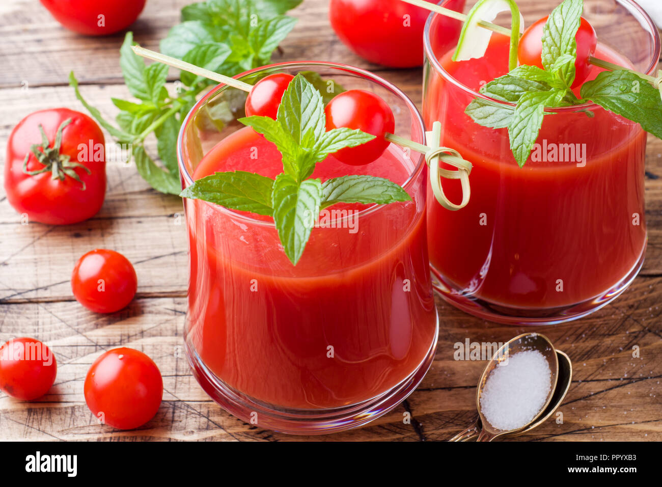 I succhi di pomodoro con la menta in vetro e pomodori freschi su un tavolo di legno. Un sano cibo organico concetto. Foto Stock