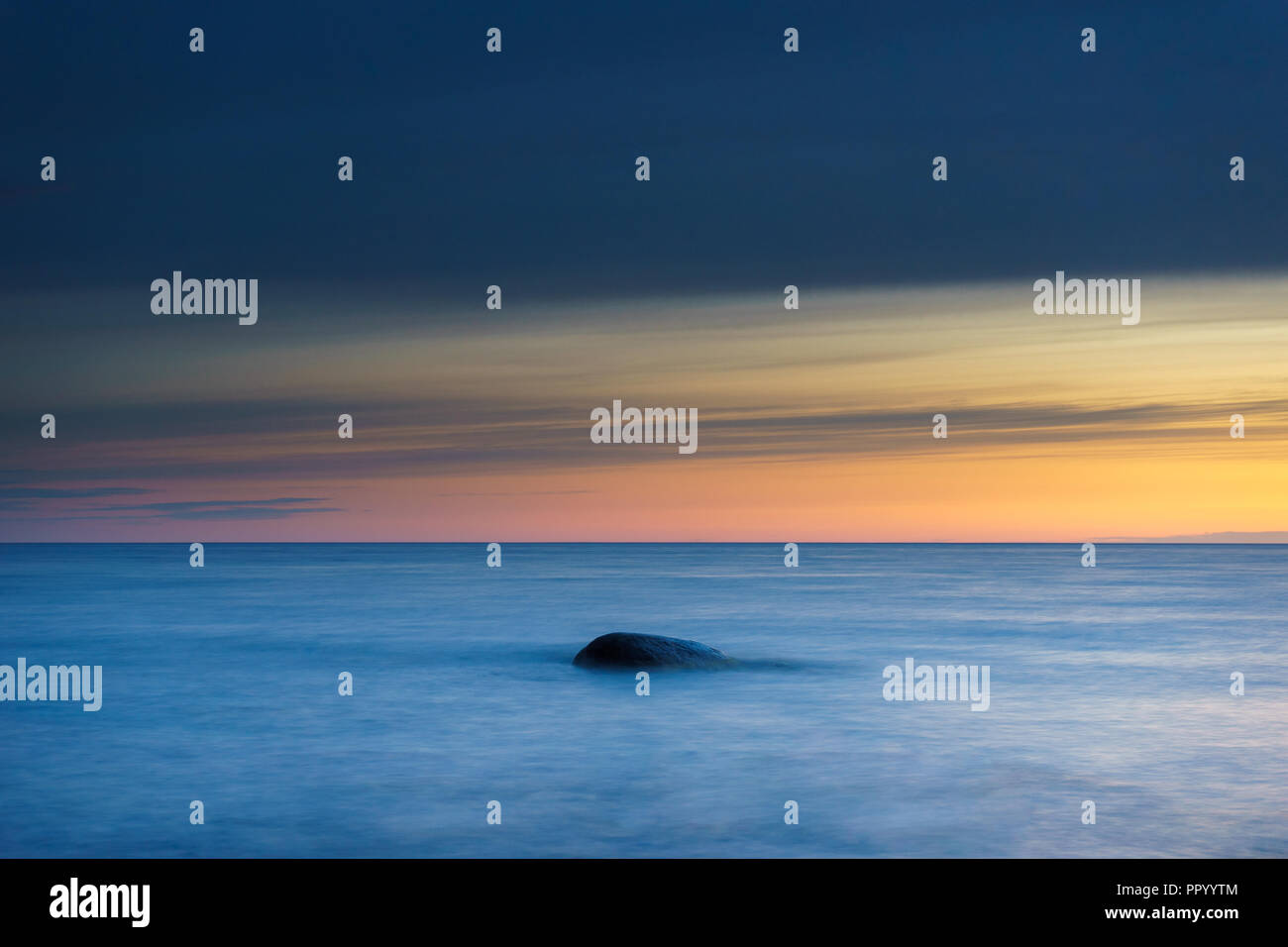 La pietra in onde del mare contro colorato cielo mattutino, una lunga esposizione shot Foto Stock