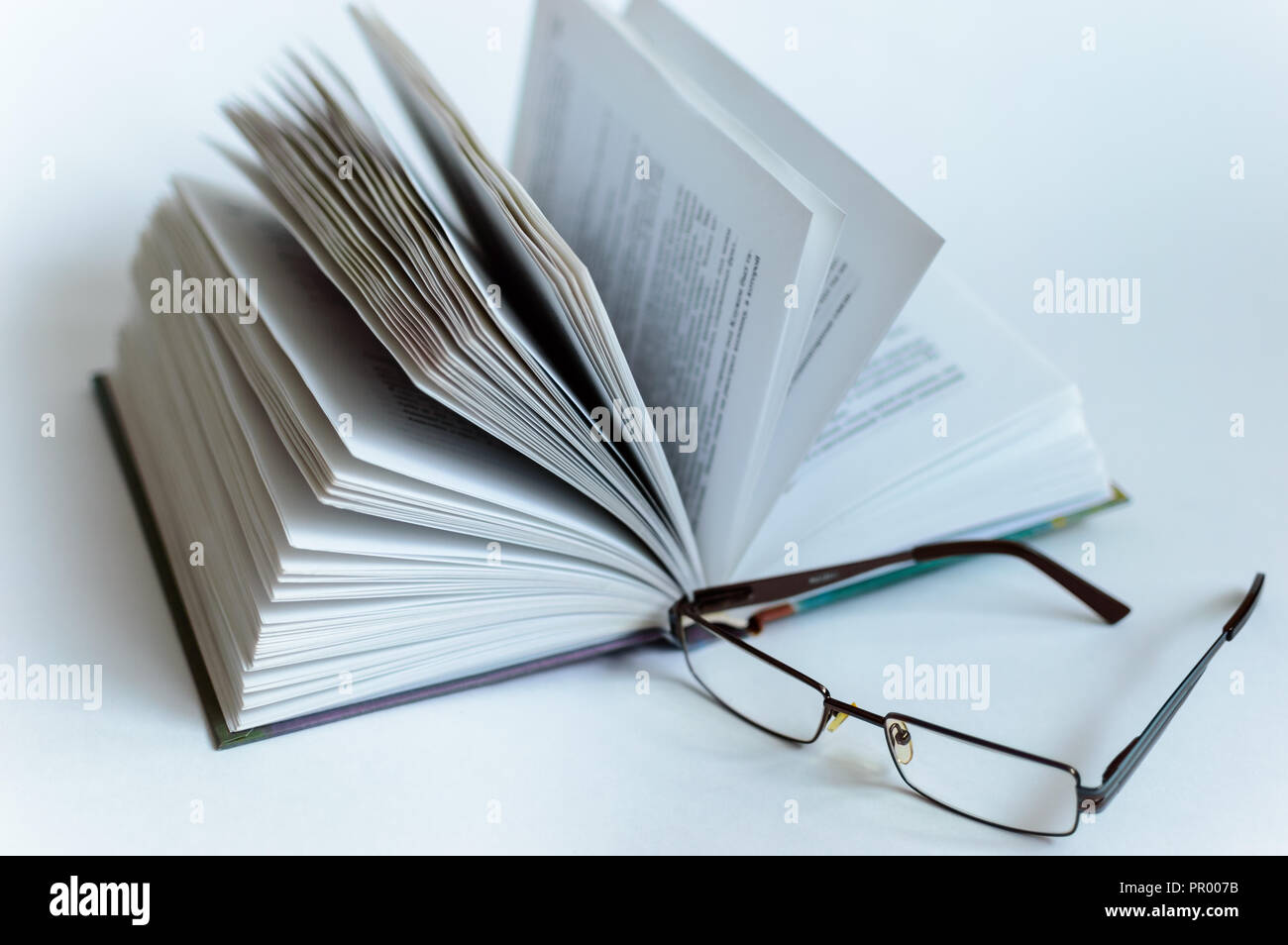 Libro Aperto giace su un fondo bianco in isolamento su uno sfondo bianco bicchieri Foto Stock