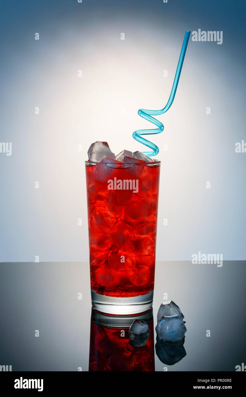 Red drink in vetro blu con paglia e cubetti di ghiaccio Foto Stock