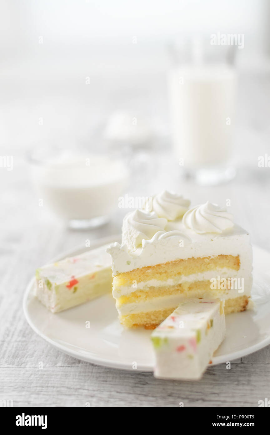 Un pezzo di torta bianca su una piastra, latte, formaggio e marshmallows Foto Stock