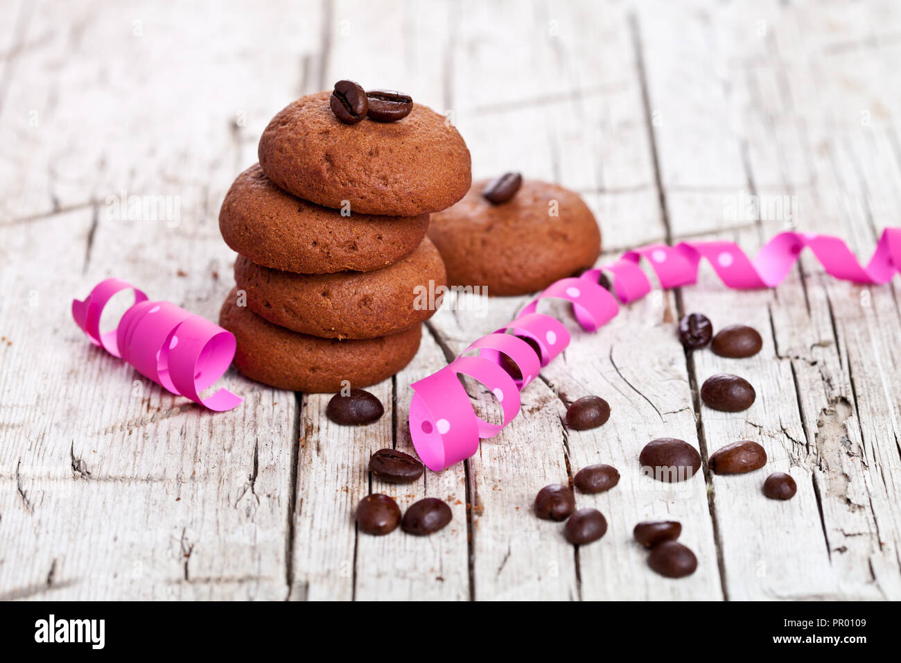 Fresco biscotti al cioccolato, i chicchi di caffè e rosa nastri su rustico sfondo di legno Foto Stock