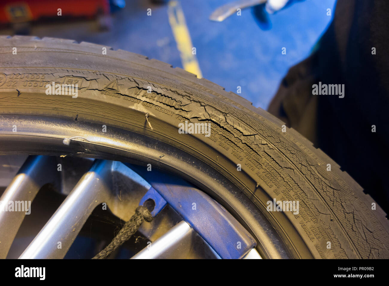 Pneumatico montatore/meccanico rimuovere / rimozione / elimina / rimozione del vecchio rotto pneumatico con il crack / crepe sulla parete laterale fianco & car / auto cerchio. Regno Unito Foto Stock