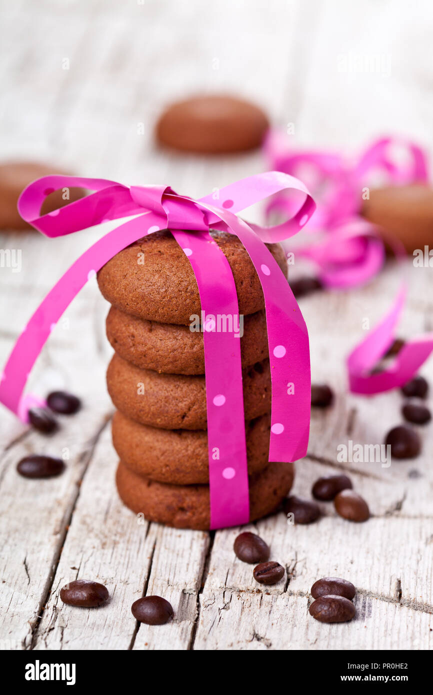 Biscotti al cioccolato legato con nastro rosa e i chicchi di caffè rustico sfondo di legno Foto Stock