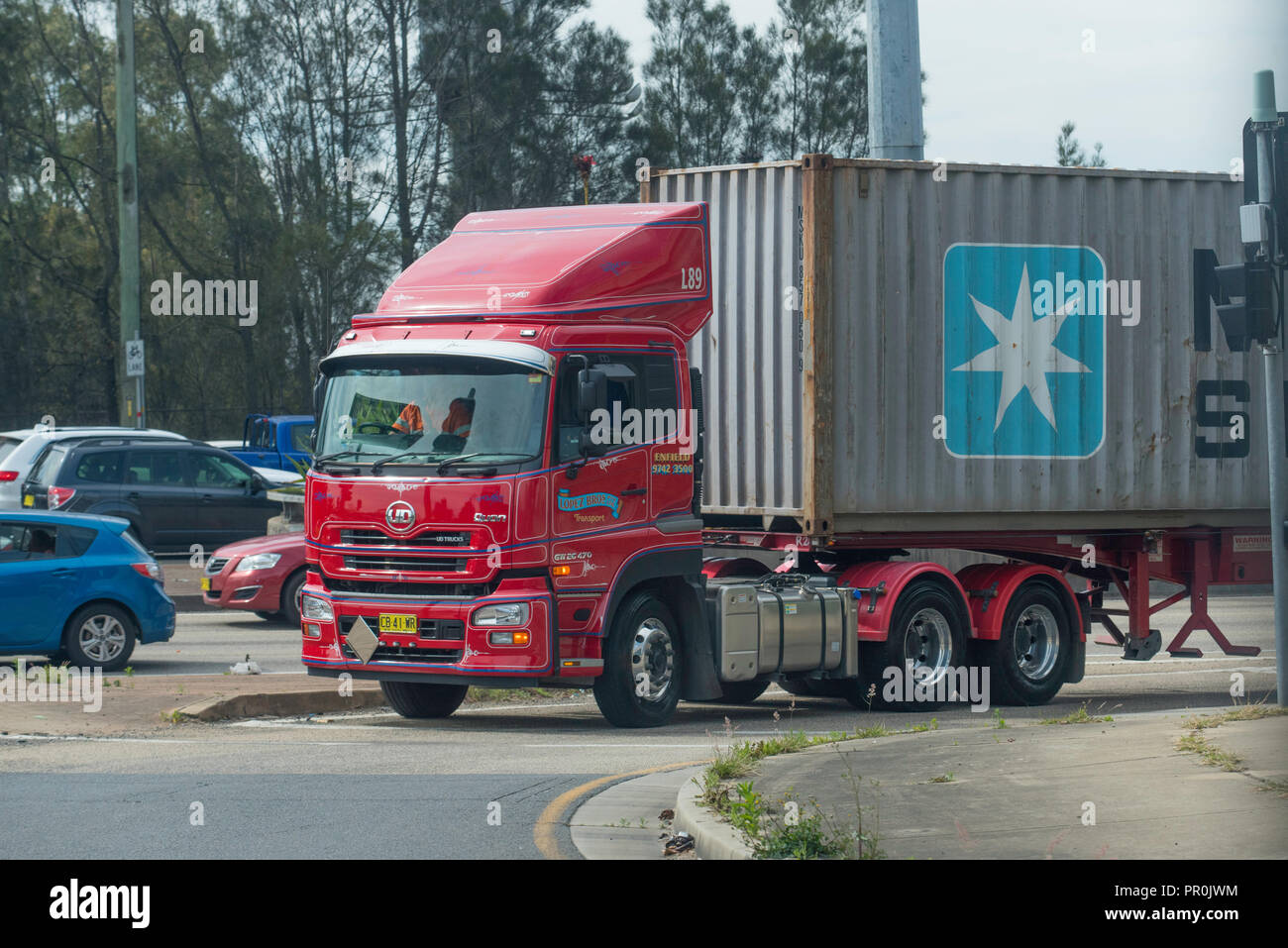 Un grande semi rimorchio camion che trasportano a Maersk Sealand contenitore di spedizione ruotando di un angolo nel traffico di Sydney, Australia Foto Stock