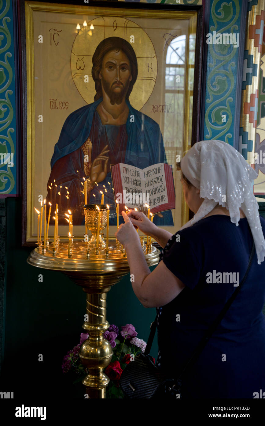 Donna accendendo candele ad una chiesa ortodossa russa service a Volgograd, Russia, Europa Foto Stock